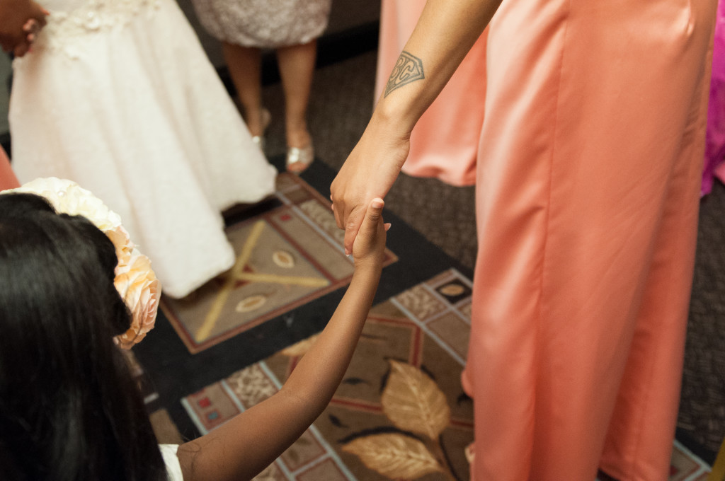 flower girl holds hand with bridesmaid during prayer before the ceremony