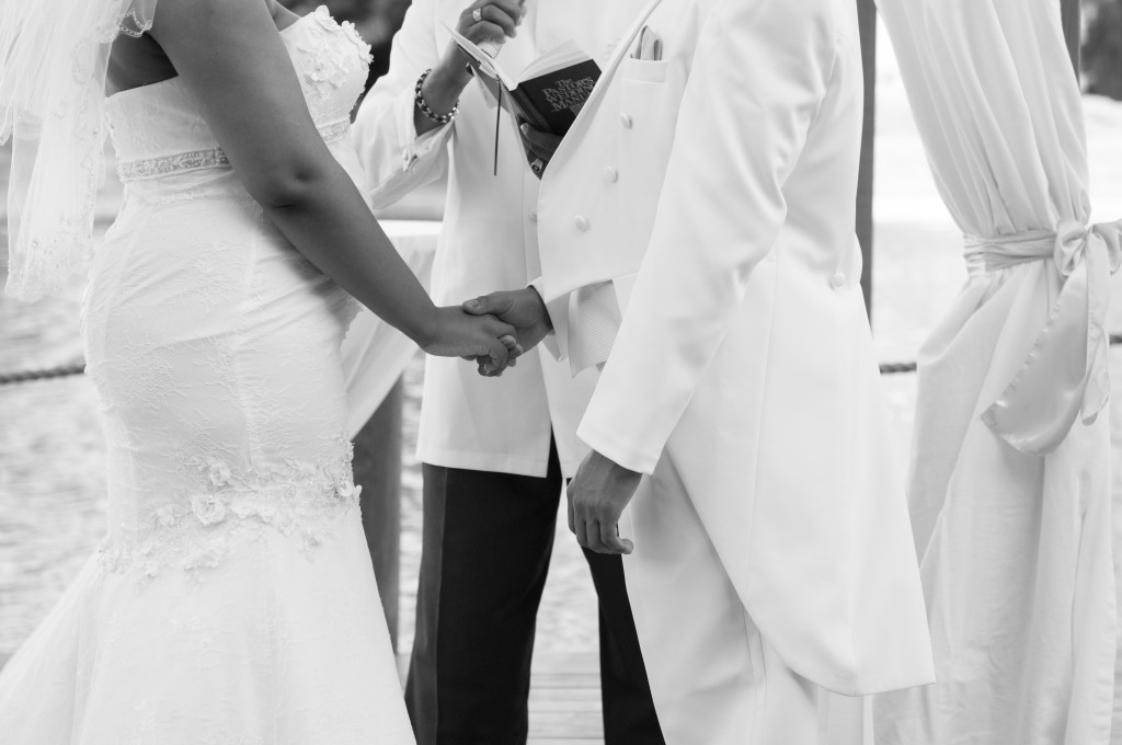 Bride and groom hold hands while minister performs ceremony
